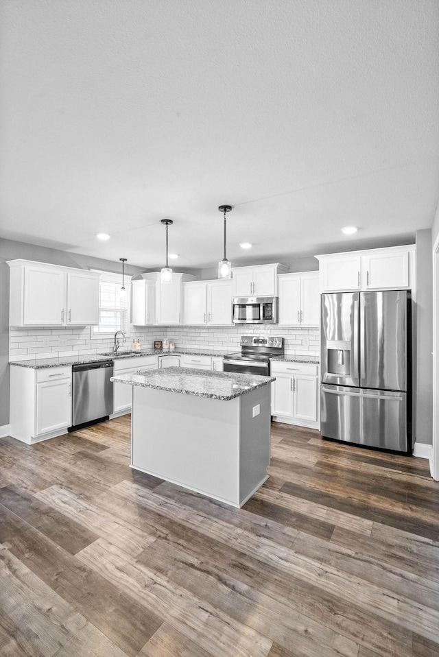 kitchen featuring backsplash, stainless steel appliances, a kitchen island, and dark wood-style flooring