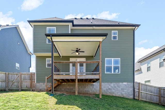 back of house with a lawn, a wooden deck, a fenced backyard, and roof with shingles