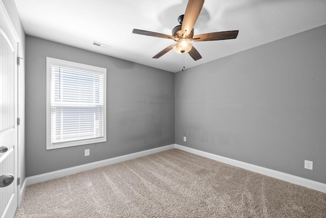 carpeted empty room featuring visible vents, baseboards, and ceiling fan