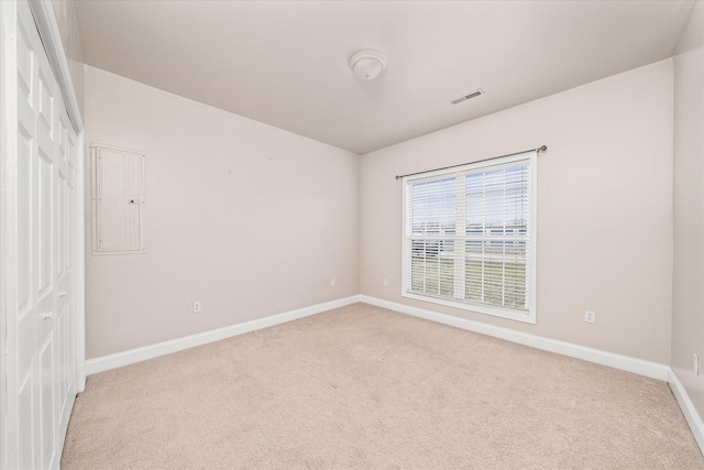 spare room with light carpet, visible vents, electric panel, and baseboards