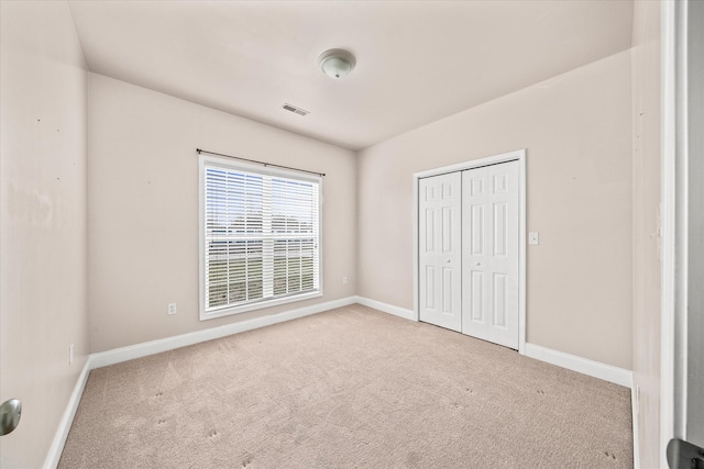 unfurnished bedroom featuring baseboards, carpet floors, visible vents, and a closet