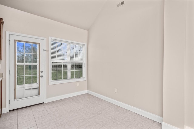 empty room featuring lofted ceiling, light tile patterned floors, baseboards, and visible vents