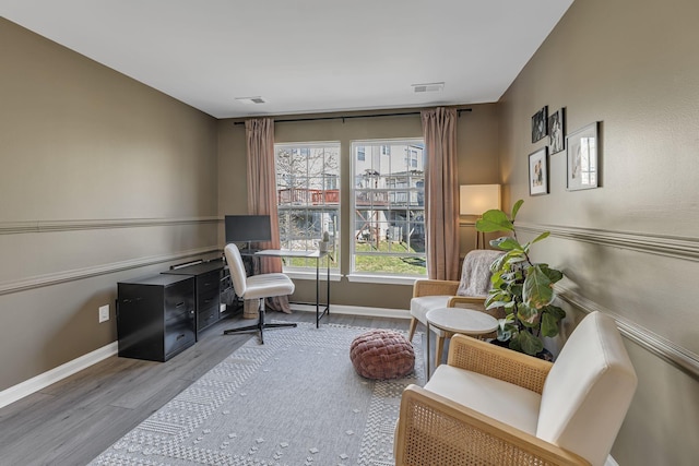 living area with wood finished floors, visible vents, and baseboards