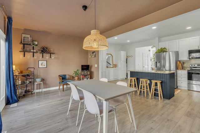 dining room with recessed lighting, light wood-type flooring, and baseboards