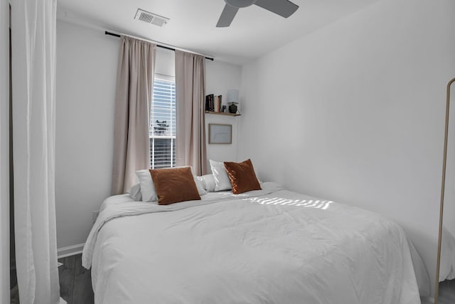 bedroom featuring baseboards, wood finished floors, visible vents, and ceiling fan