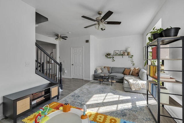 living area featuring baseboards, stairs, ceiling fan, and wood finished floors