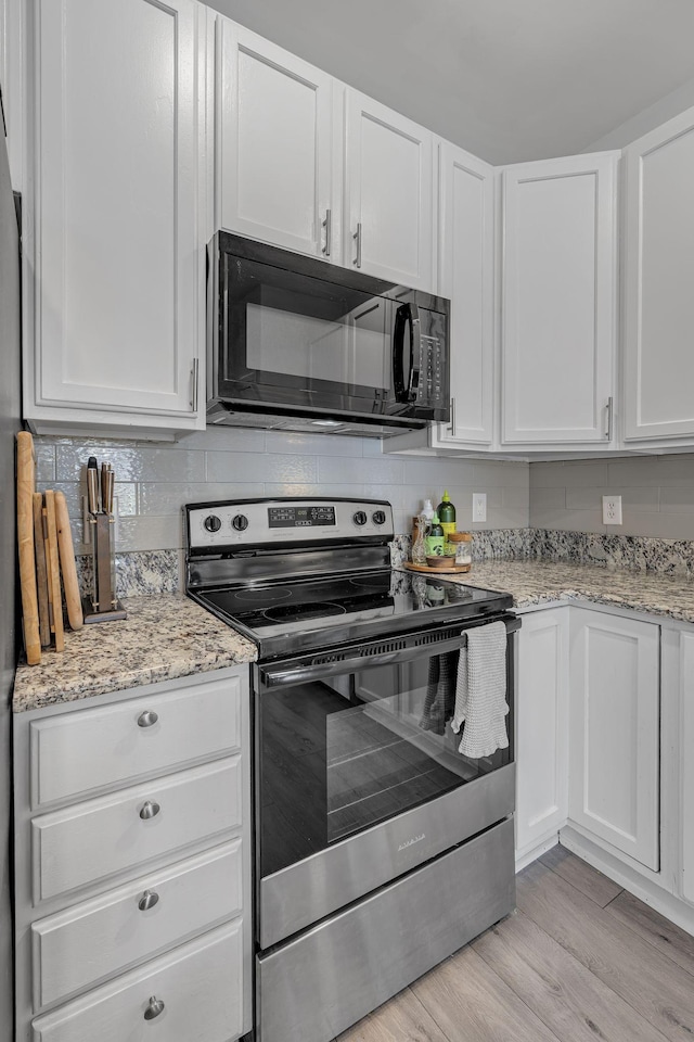 kitchen featuring electric range, light wood-style flooring, white cabinetry, and black microwave