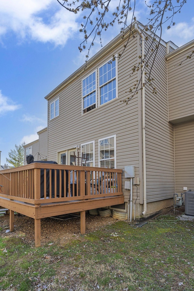 rear view of house featuring central air condition unit, a lawn, and a wooden deck