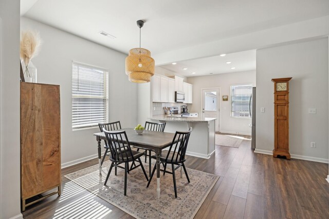 dining space featuring dark wood finished floors, plenty of natural light, baseboards, and visible vents