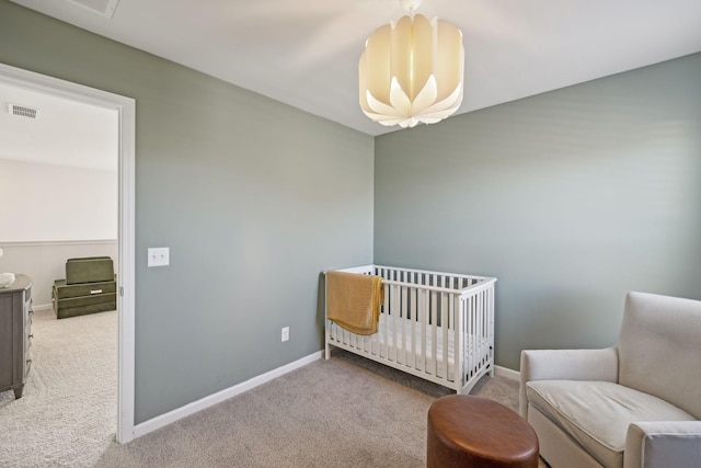 bedroom with carpet flooring, visible vents, a crib, and baseboards