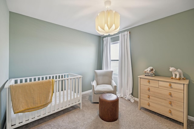 carpeted bedroom with baseboards, a nursery area, and an inviting chandelier