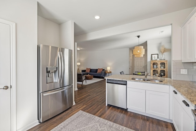 kitchen featuring dark wood finished floors, a peninsula, a sink, stainless steel appliances, and white cabinets