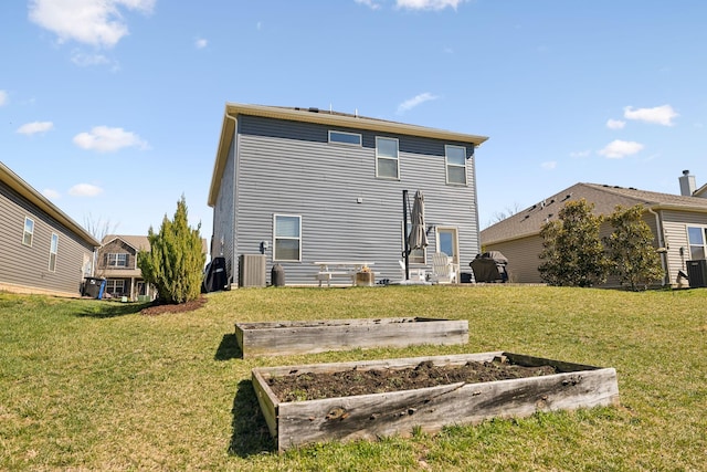 rear view of house featuring a lawn, central AC, and a vegetable garden