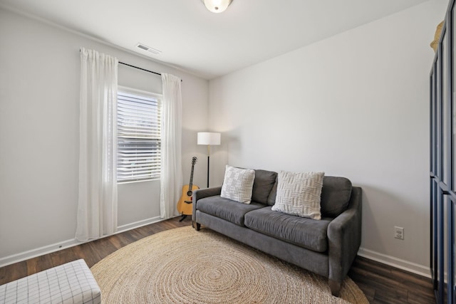 living area featuring visible vents, baseboards, and wood finished floors