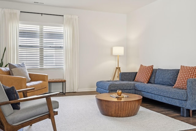 living area featuring baseboards, a healthy amount of sunlight, and wood finished floors