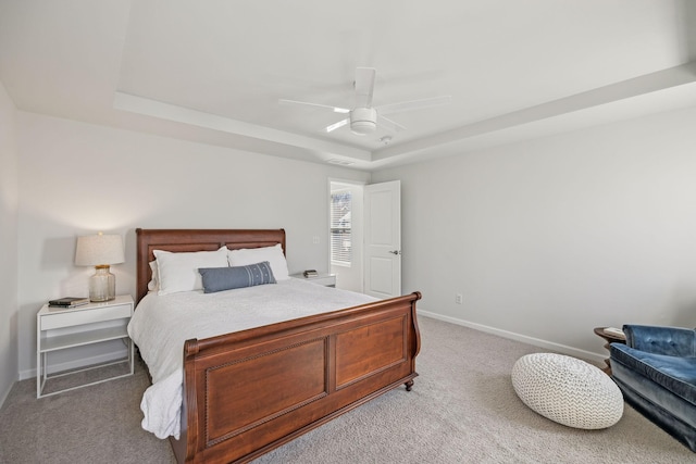 carpeted bedroom featuring a raised ceiling, a ceiling fan, and baseboards