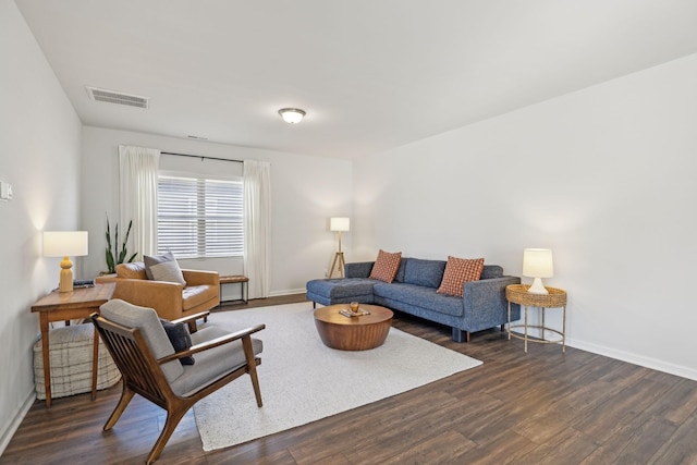 living room with visible vents, baseboards, and dark wood finished floors