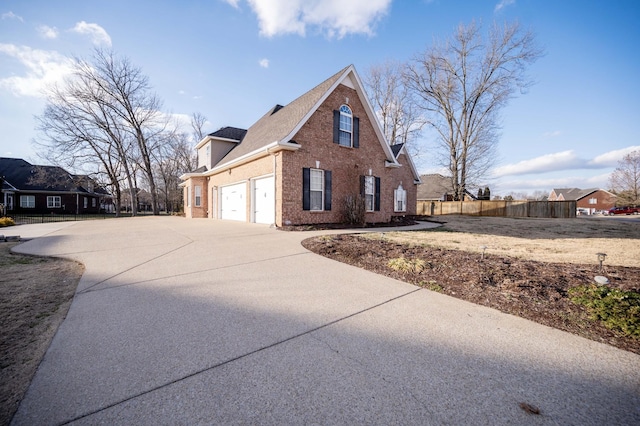 view of side of property featuring concrete driveway, a garage, fence, and brick siding