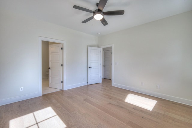 unfurnished bedroom featuring light wood-style flooring, a ceiling fan, ensuite bathroom, and baseboards