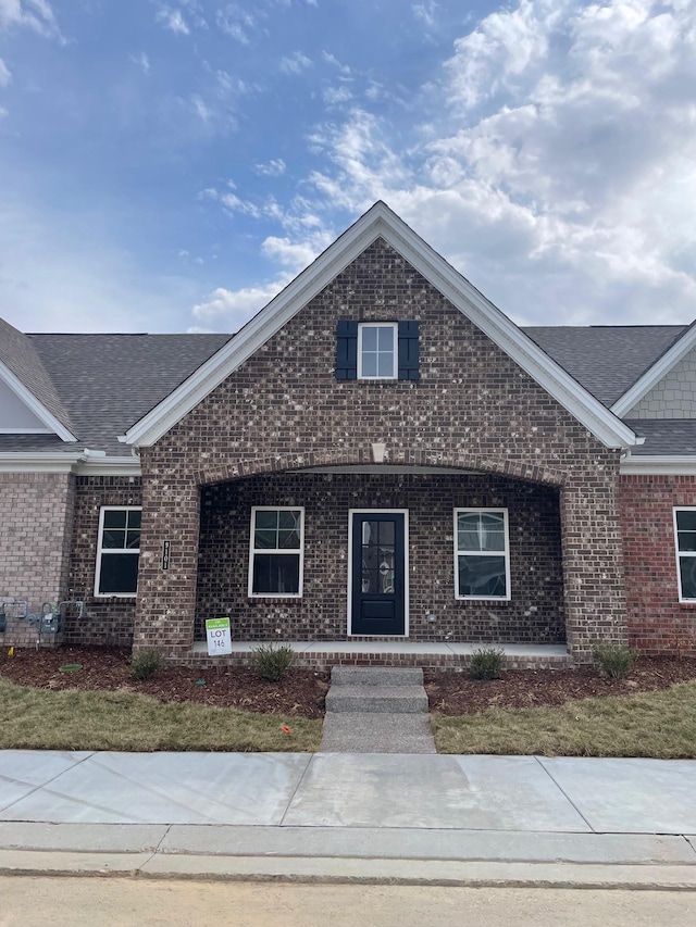 view of front of property with brick siding and roof with shingles