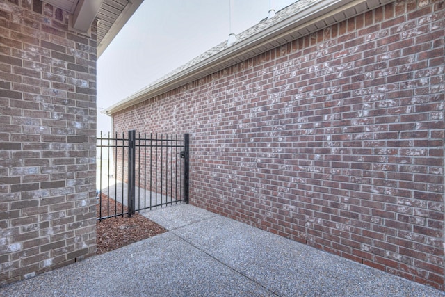 view of side of property with fence, brick siding, and a gate