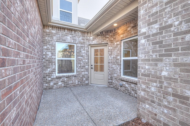 doorway to property featuring a patio area and brick siding