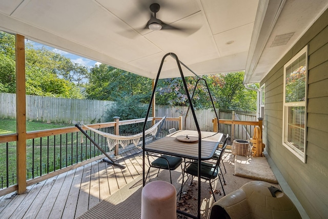 wooden terrace with outdoor dining space, ceiling fan, and a fenced backyard