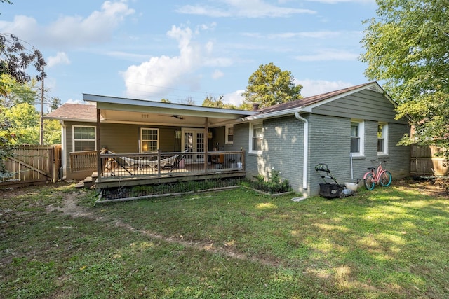 back of house with a yard, brick siding, a deck, and fence