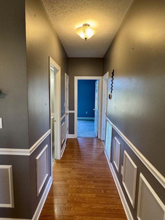 corridor featuring a textured ceiling and wood finished floors