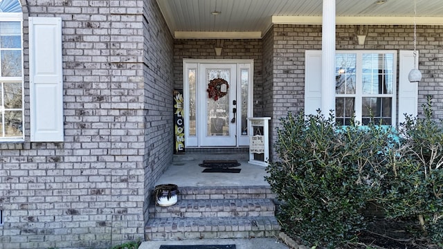 property entrance with a porch and brick siding