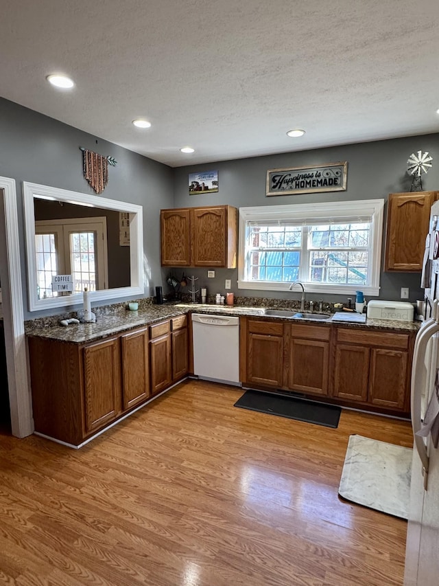 kitchen with white appliances, brown cabinets, and a sink