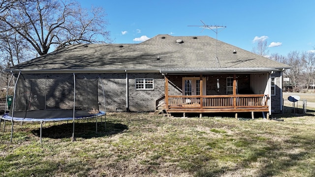 back of house with a deck, a trampoline, a yard, crawl space, and brick siding