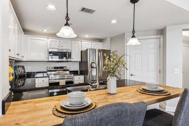 kitchen with visible vents, a sink, wood counters, appliances with stainless steel finishes, and white cabinets