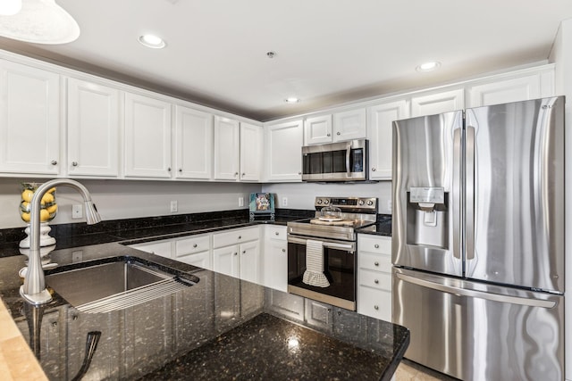 kitchen featuring dark stone countertops, recessed lighting, a sink, white cabinets, and appliances with stainless steel finishes