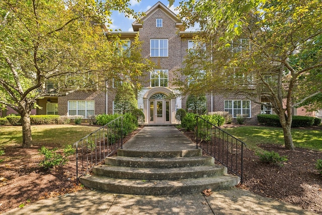 view of front of home featuring a front lawn, french doors, and brick siding