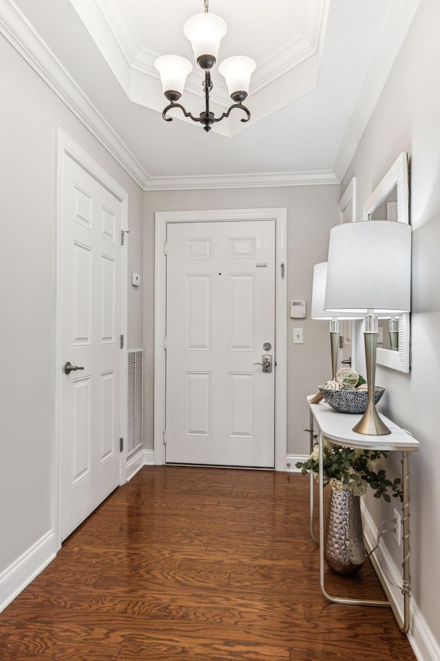 entryway featuring a tray ceiling, wood finished floors, and a chandelier