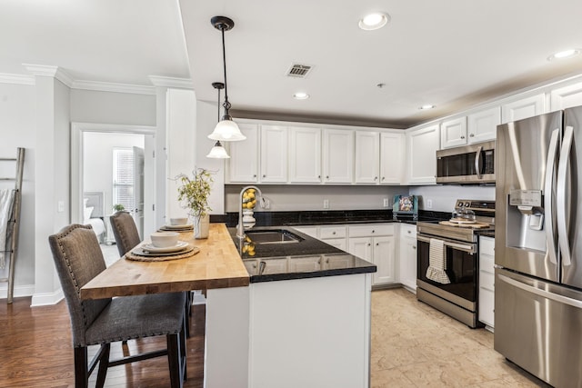 kitchen featuring visible vents, a peninsula, a sink, white cabinets, and appliances with stainless steel finishes