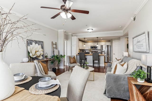 living room with visible vents, ceiling fan, baseboards, ornamental molding, and light wood-style floors