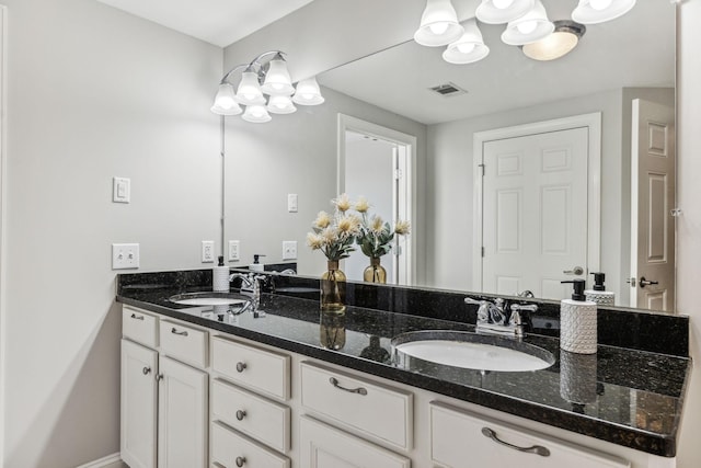 full bathroom with double vanity, a notable chandelier, visible vents, and a sink