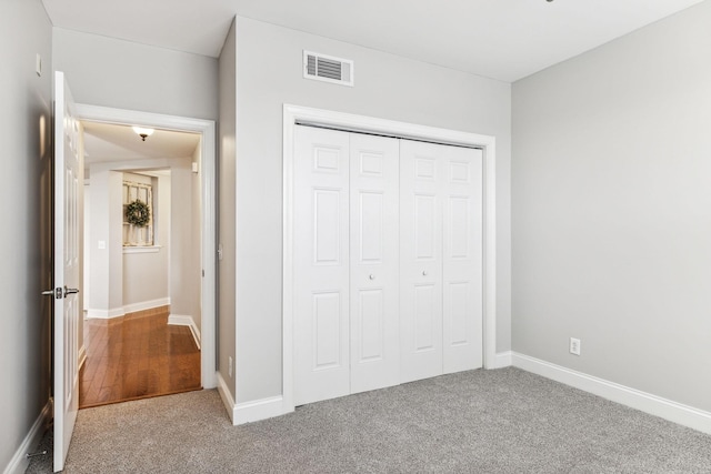 unfurnished bedroom with carpet, visible vents, a closet, and baseboards