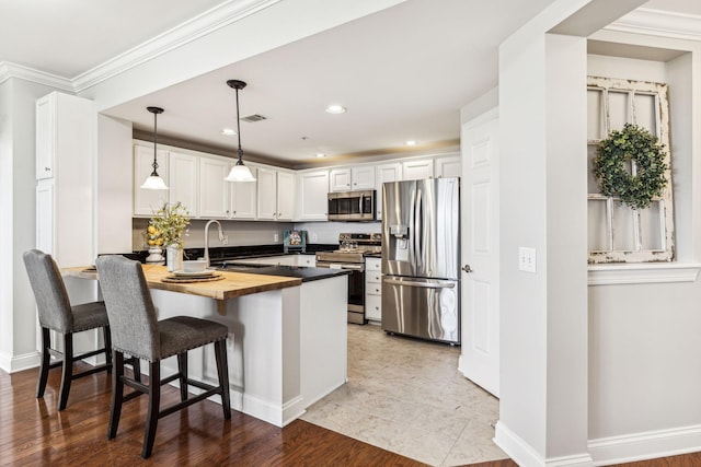 kitchen with visible vents, wooden counters, a peninsula, stainless steel appliances, and a sink