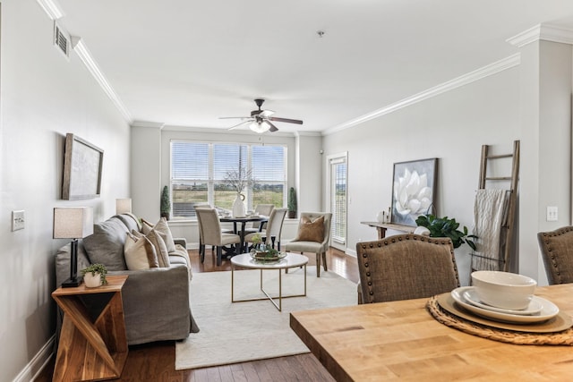 living room featuring ceiling fan, baseboards, wood finished floors, and crown molding