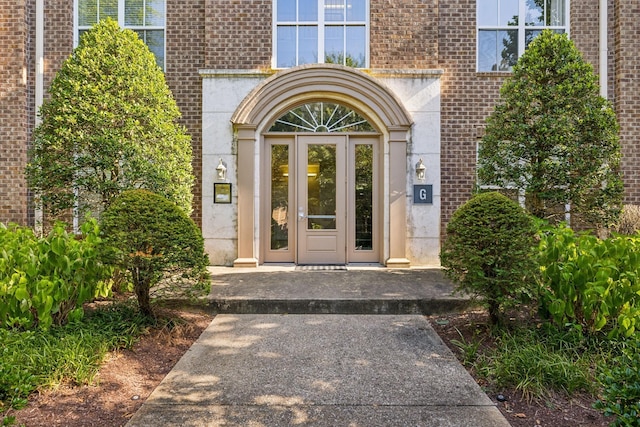 view of exterior entry featuring french doors and brick siding