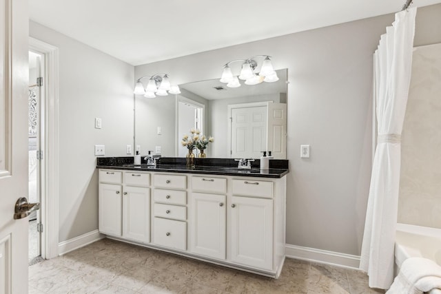 bathroom featuring double vanity, a tub to relax in, baseboards, and a sink