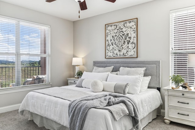 bedroom featuring multiple windows, light carpet, baseboards, and ceiling fan