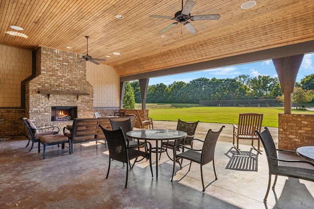 view of patio / terrace featuring an outdoor living space with a fireplace, outdoor dining space, and a ceiling fan