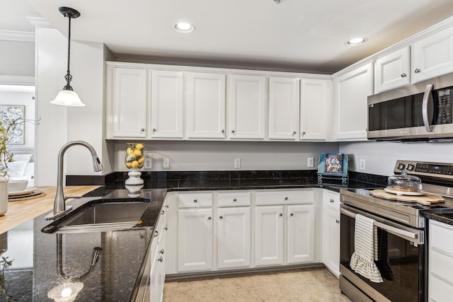 kitchen featuring decorative light fixtures, recessed lighting, appliances with stainless steel finishes, white cabinets, and a sink