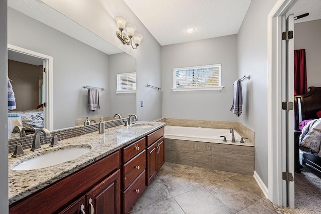 bathroom with a textured ceiling, a garden tub, ensuite bathroom, and a sink