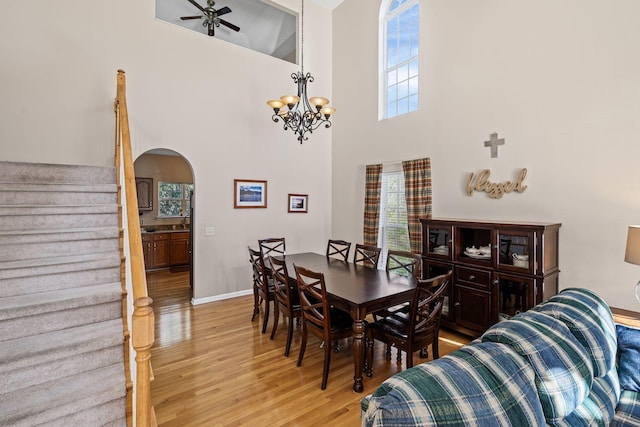 dining area with arched walkways, stairway, a healthy amount of sunlight, and light wood-type flooring