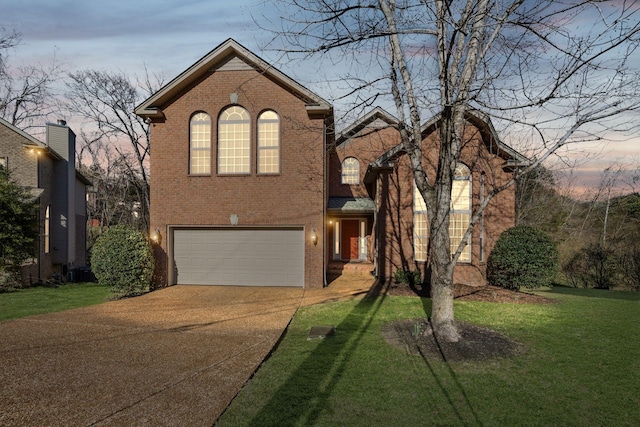 traditional home with brick siding, a lawn, driveway, and a garage